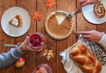 person slicing pie beside bread